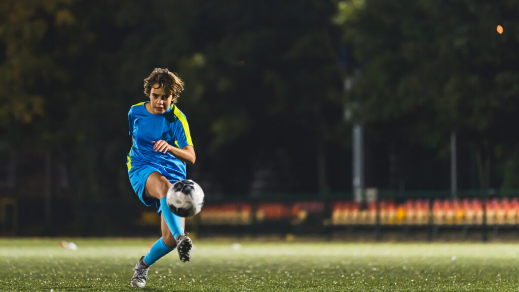 Jeune joueur frappant le ballon pendant un match de tournoi de football
