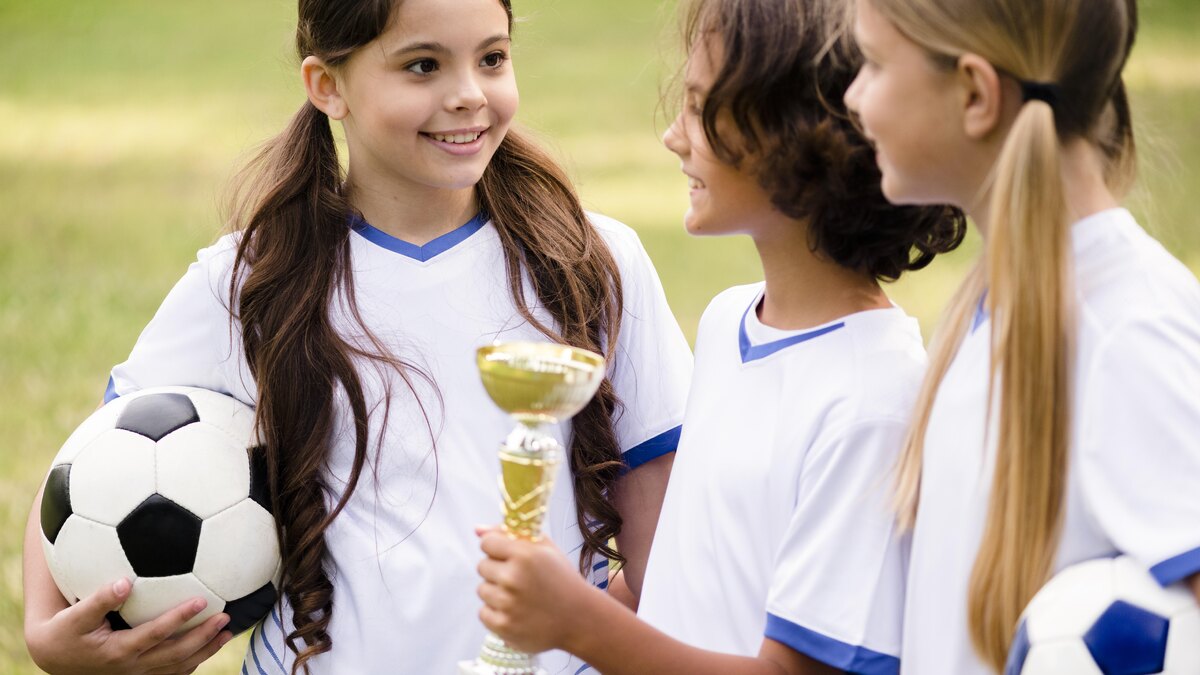 Jeunes joueuses posant avec le trophée remporté lors d'un tournoi de football